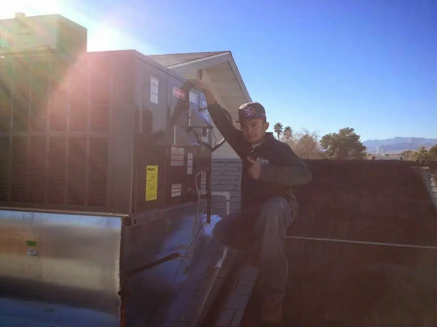 HVAC technician performing AC Tune-Up on a rooftop unit in Central